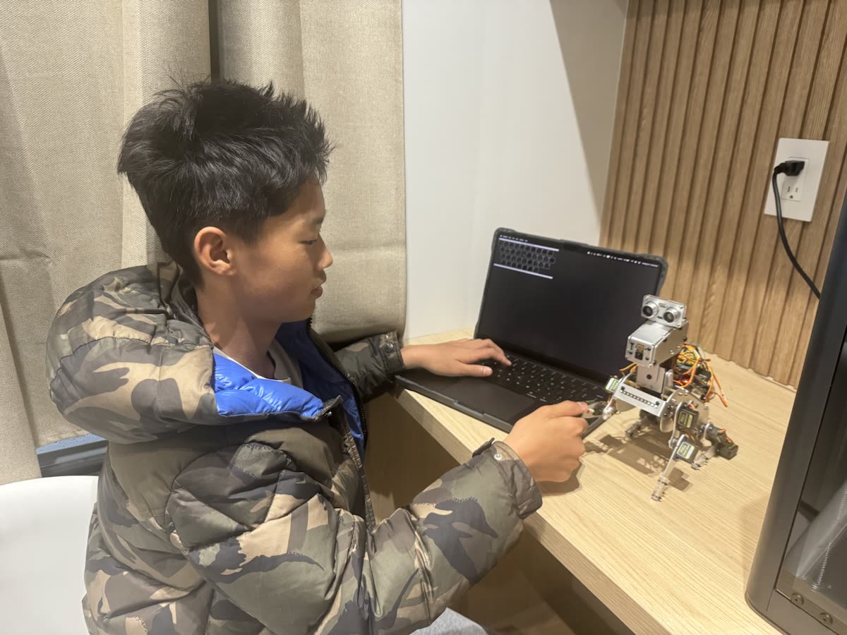 Edwin testing the Smart Dog robot beside a laptop